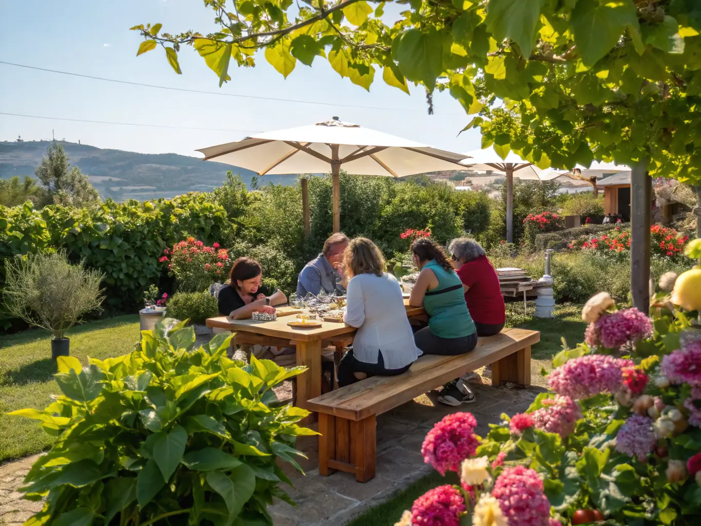 A photograph capturing a group of people laughing and sharing food at a communal meal in a sunny outdoor setting.